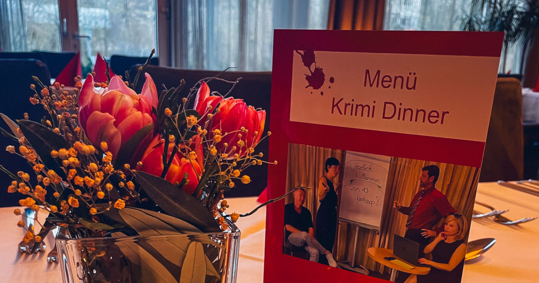 Menü Krimi Dinner und eine kleine Vase mit Blumen. Im Hintergrund gedeckte Tische.
