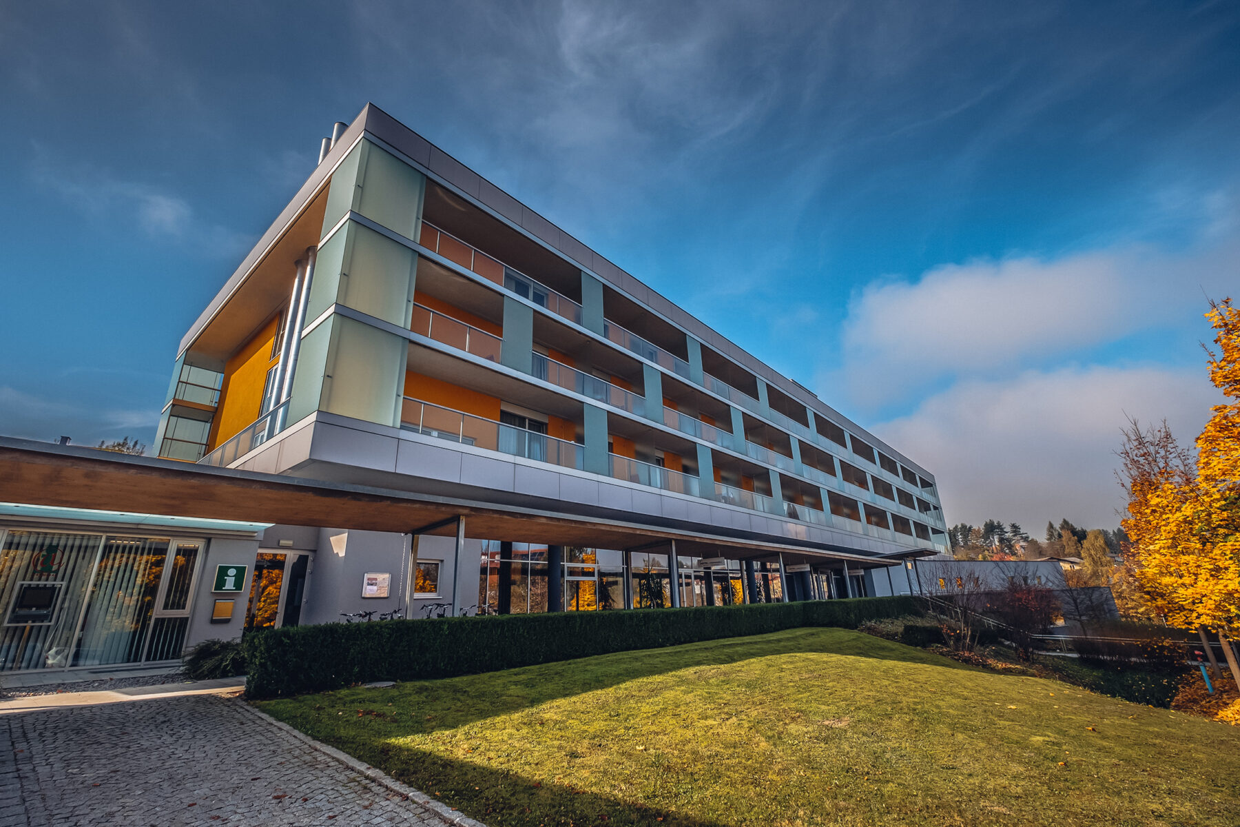 Hotel Lebensquell mit herbstlichen Bäumen und blauem Himmel.
