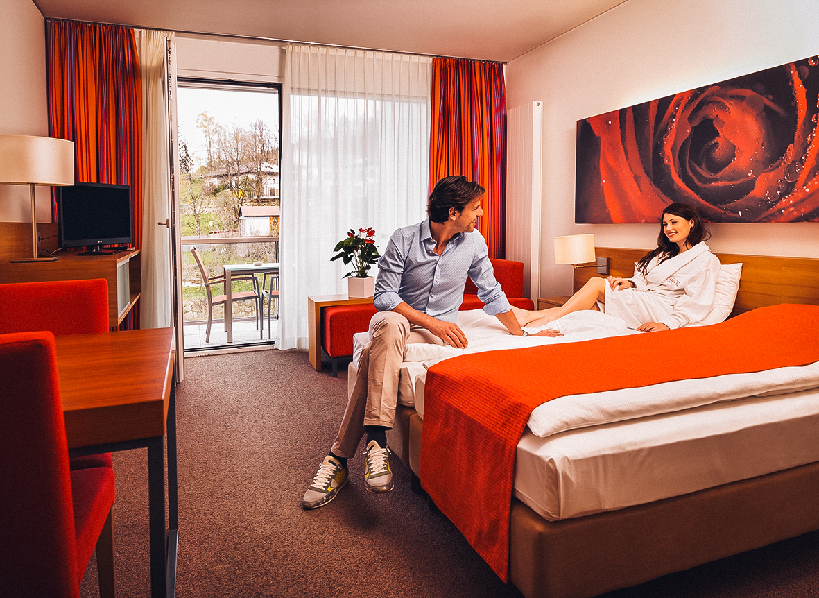 Paar sitzt entspannt im Bett am Zimmer