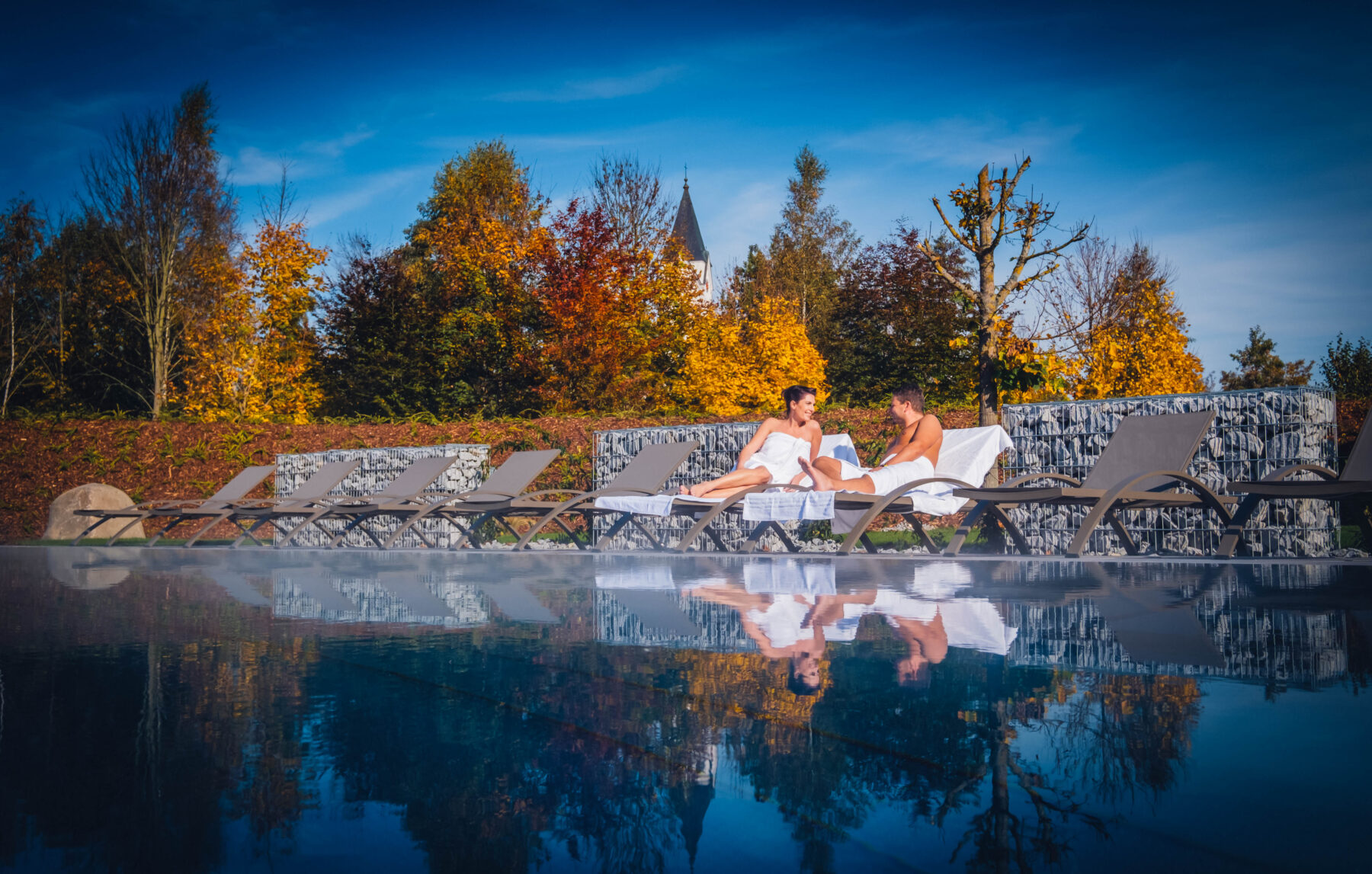 Paar entspannt auf der Liege im Saunabereich neben dem Pool
