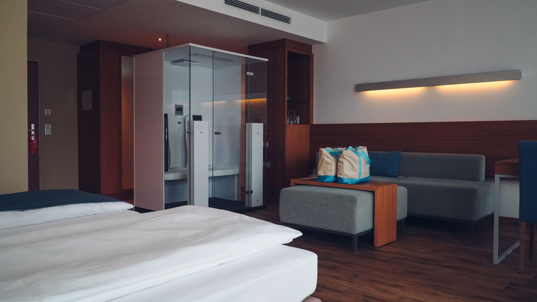 Hotelzimmer mit Infrarotkabine und am Couchtisch sind zwei Badetaschen platziert.