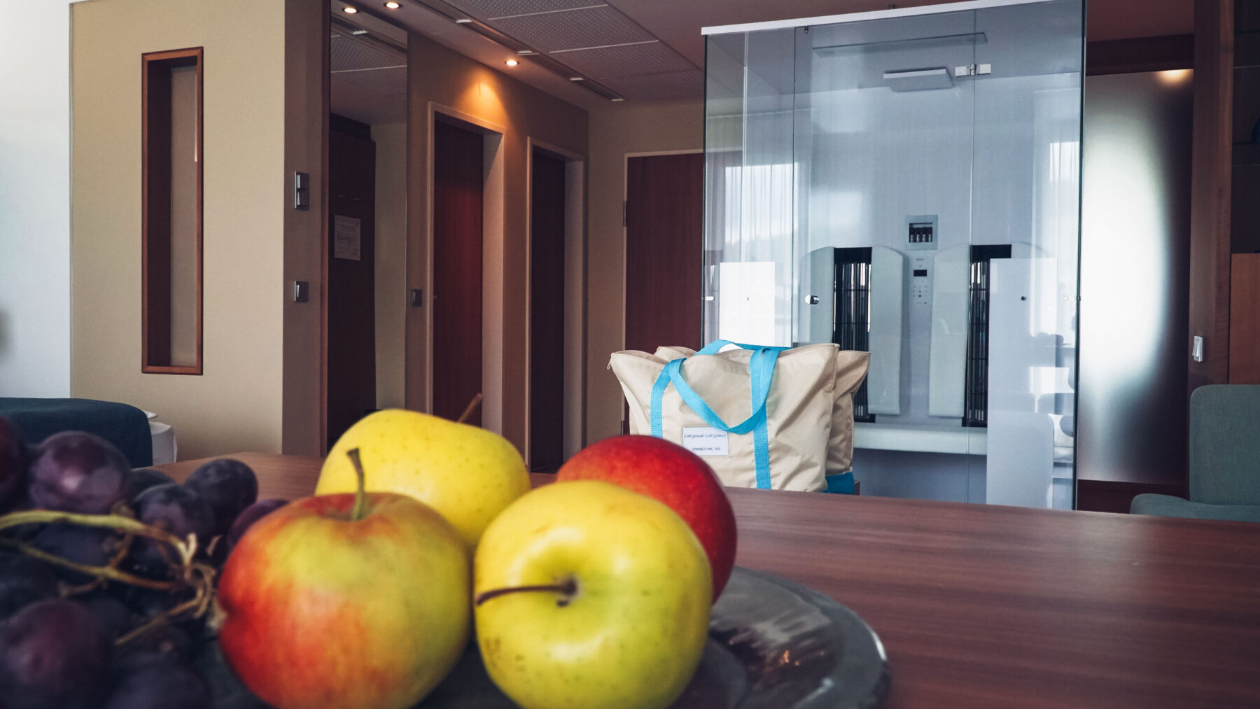 Auf einem Tisch ist Obst platziert und im Hintergrund ist die Infrarotkabine und Badetaschen zu erkennen.