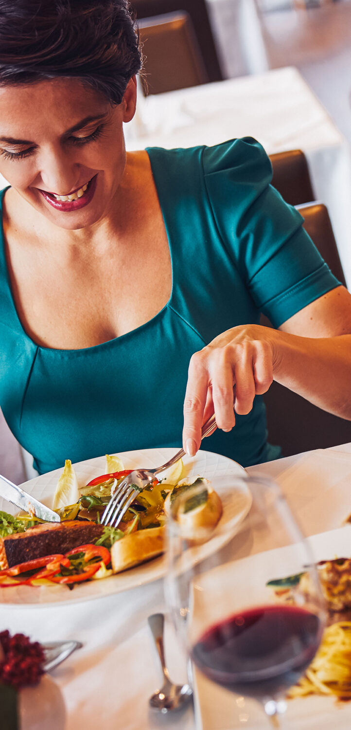 Eine Dame, welches Ihr Abendessen und ein Glas Rotwein genießt