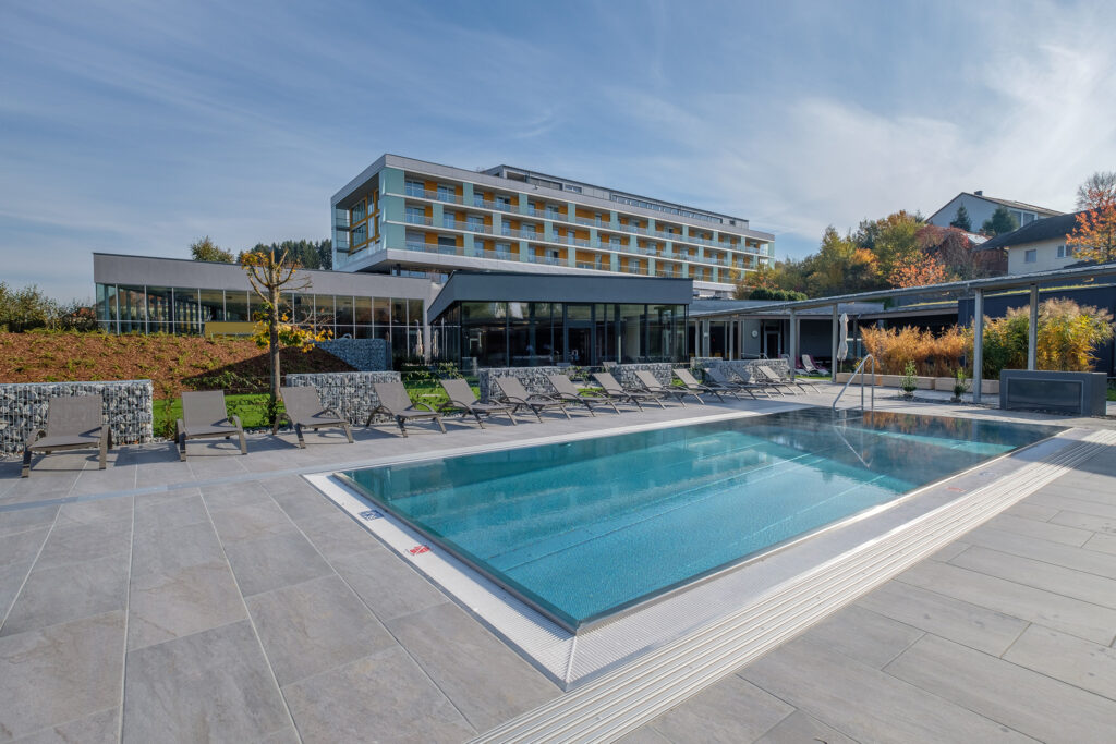 Hotel Lebensquell mit Außenpool und Liegebereich mit blauem Himmel