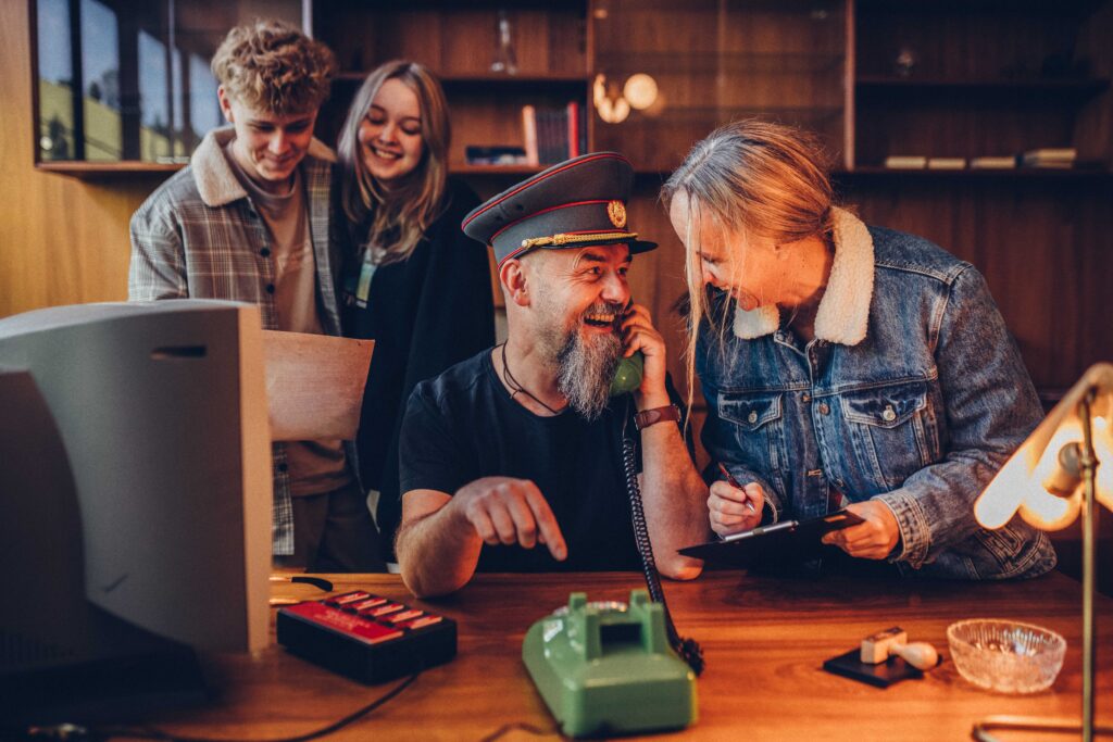 Man sieht vier Personen, welche gerade am lösen eines Escape-Rooms sind.