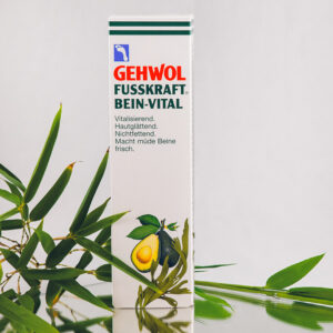 Man sieht die Fusskraft-Bein-Vital-Creme mit grünen Blättern im Hintergrund