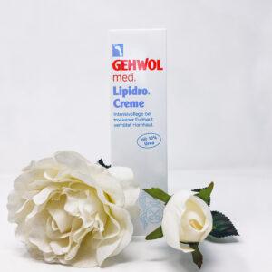 Man sieht die Lipidro Creme mit zwei weißen Blumen vor dem Produkt