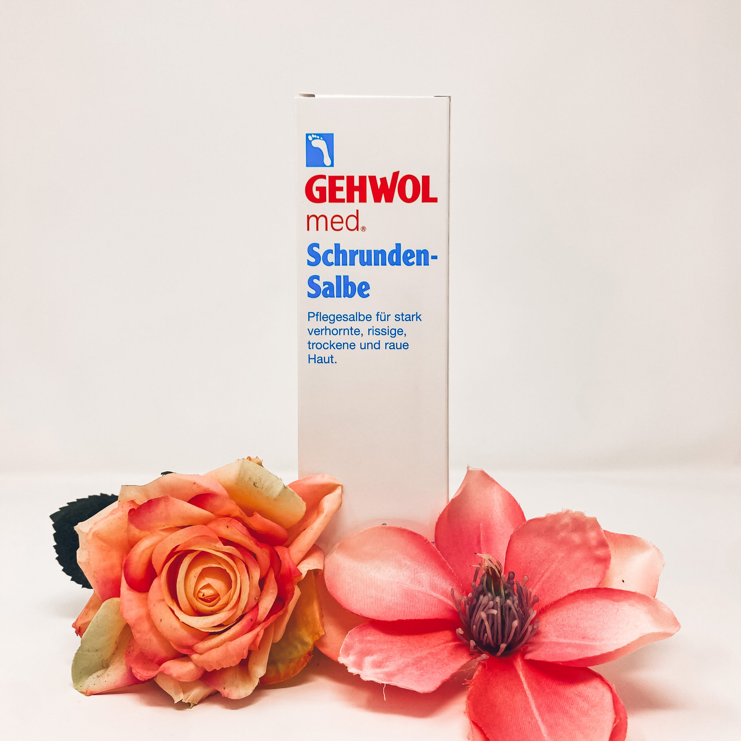 Schrudnen-Salbe mit Blumen, welche neben der Verpackung liegen