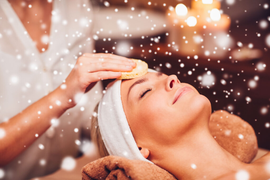 Eine Frau genießt eine Gesichtsbehandlung mit einem Schwamm, umgeben von sanftem Schneefall.