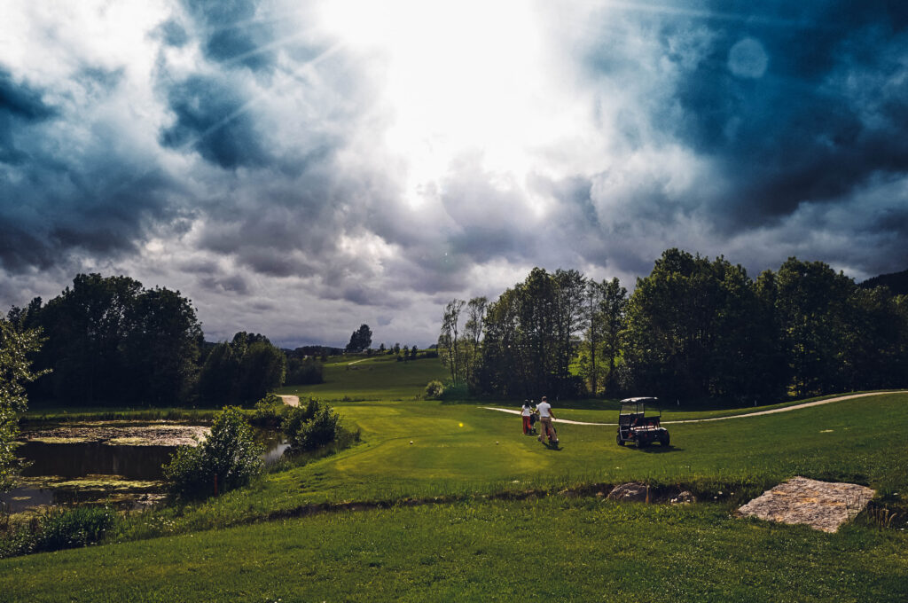 Man sieht einen Golfplatz, welcher von 2 Personen genutzt wird.