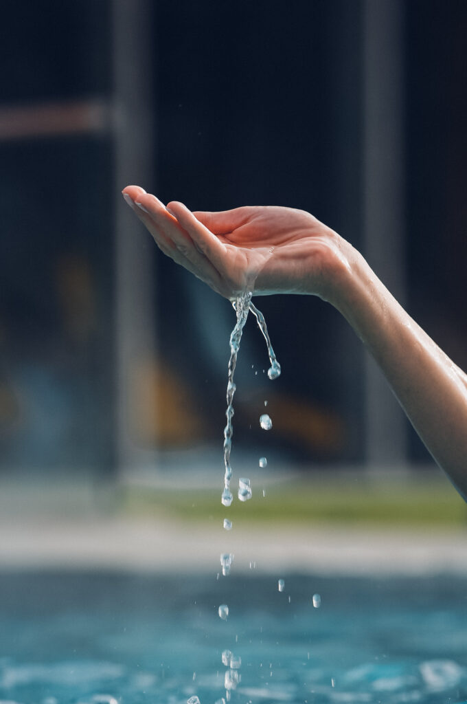 Man sieht eine Hand wo langsam das Wasser runterfliest ins Becken.