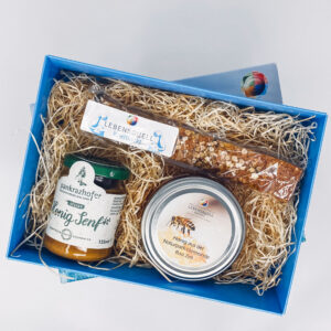 Geschenkbox gefüllt mit einem Müsli8riegel, einem Honig und Honigsenf.