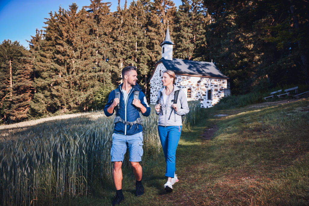 Ein Paar wandert von der Bergkapelle Kammererkreuz herunter.