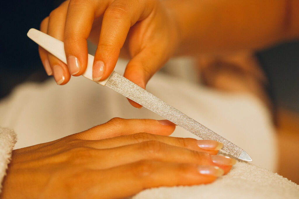 Die Fingernägel einer Frau werden gefeilt.