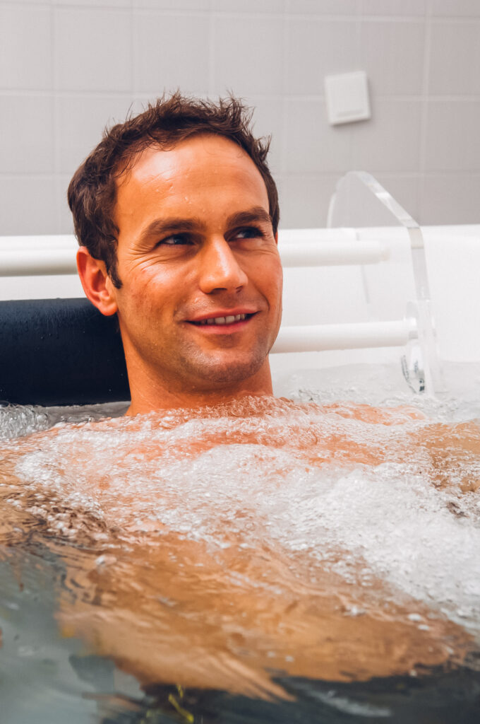 Mann entspannt in einem sprudelnden Kohlensäurebad mit leichtem Lächeln.