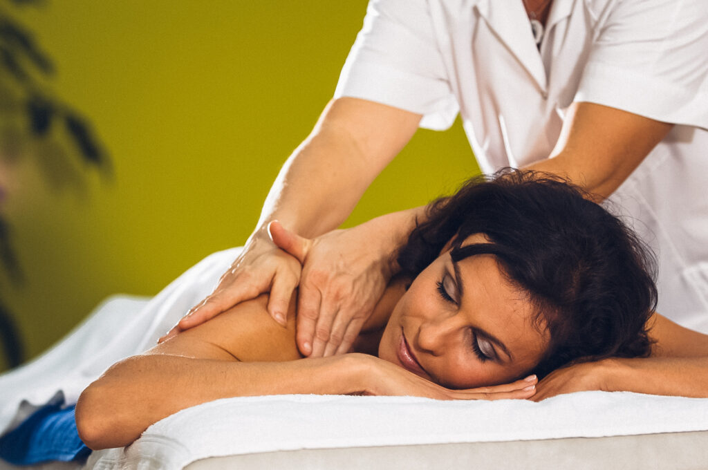 Frau wird auf Massageliege massiert auf der rechten Schulter.