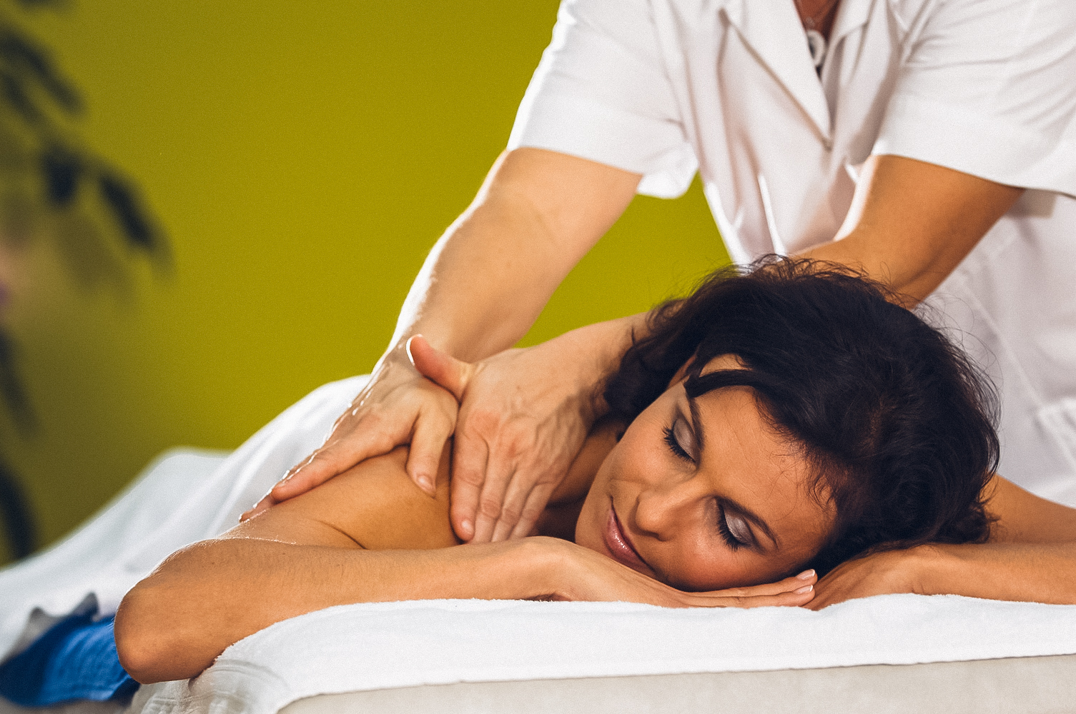 Frau wird auf Massageliege massiert auf der rechten Schulter.