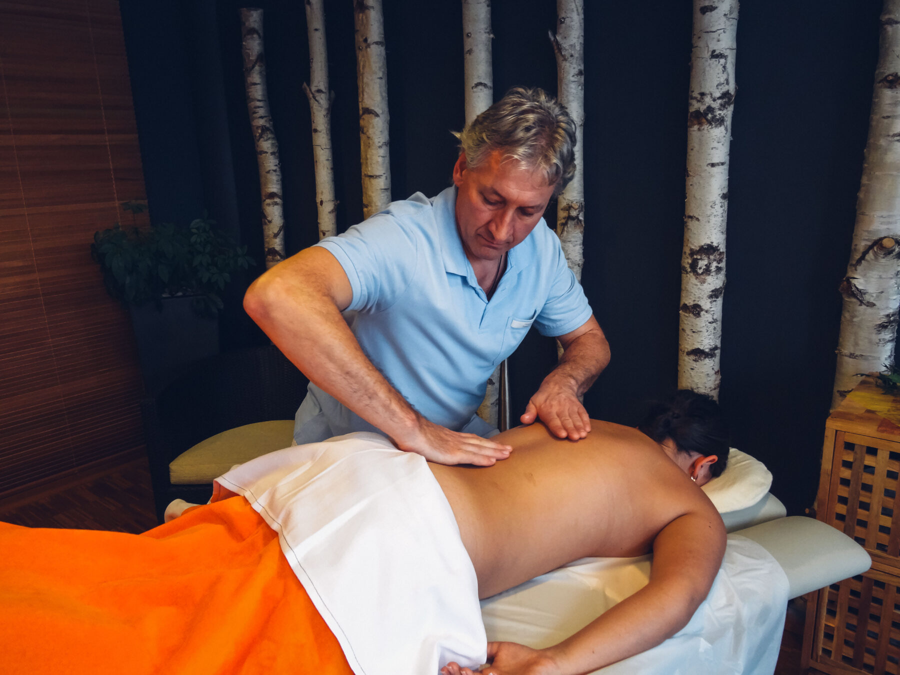 Ein Therapeut massiert den Rücken einer jungen Dame.