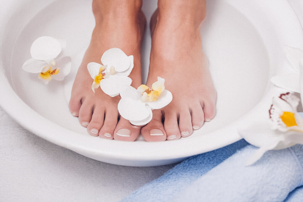 Füße die in einer Schüssel mit Wasser sind und ebenfalls mit Blumen dekoriert sind.