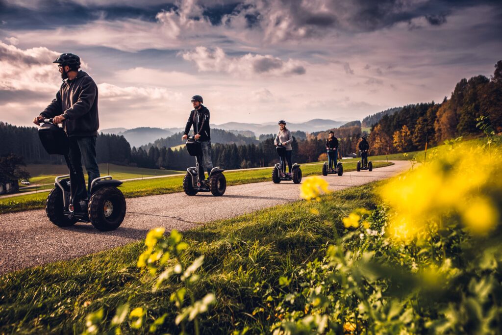 Eine Gruppe fährt im Mühlviertel hintereinander auf einer Straße mit Segways.