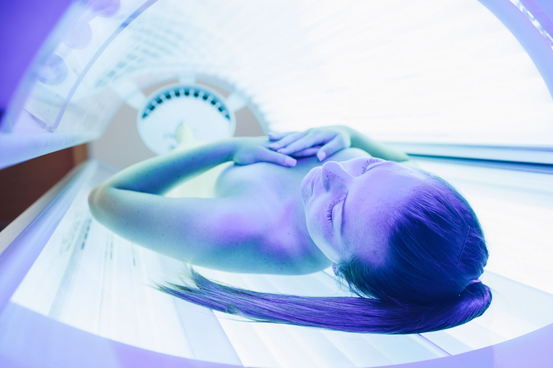 Frau liegt im Solarium und lässt sich bräunen.