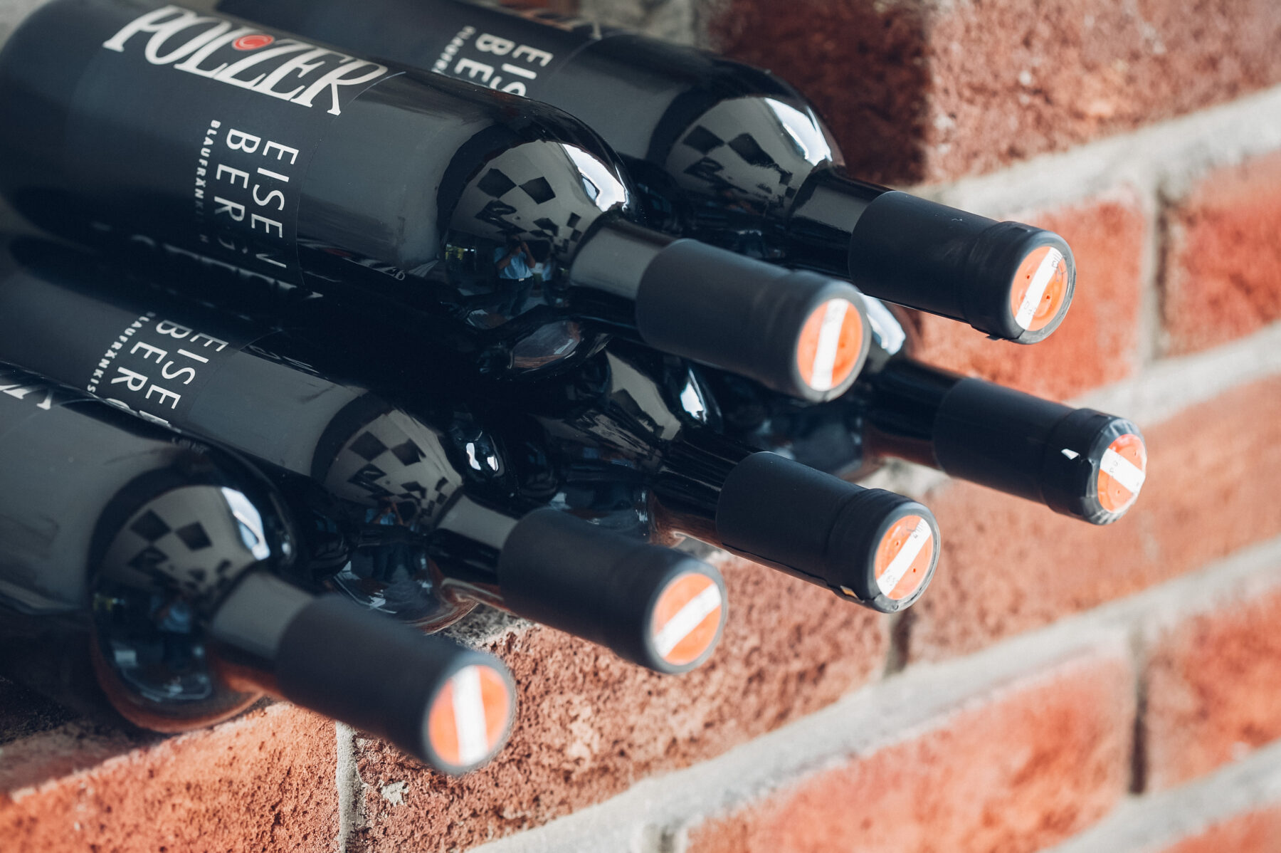 Man sieht sechs Rotweinflaschen, welche in zwei Reihen übereinander liegen.