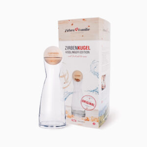 Man sieht die Verpackung und eine Wasserkarave mit einer Zirbenkugel als Deckel